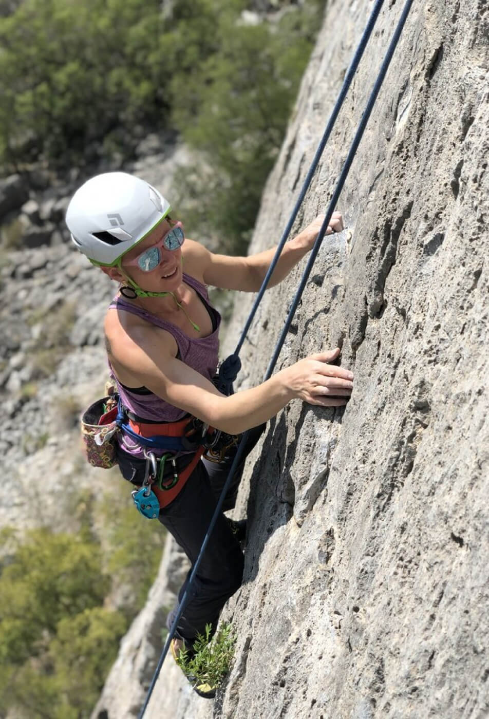A woman calculating her next course of action while rock climbing.