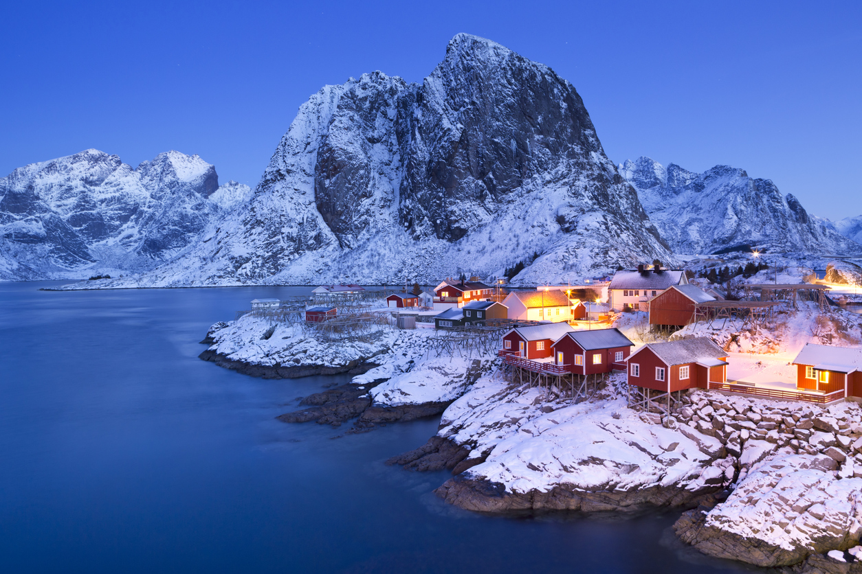 View of a fishing village and snow-covered mountains in Lofoten during night