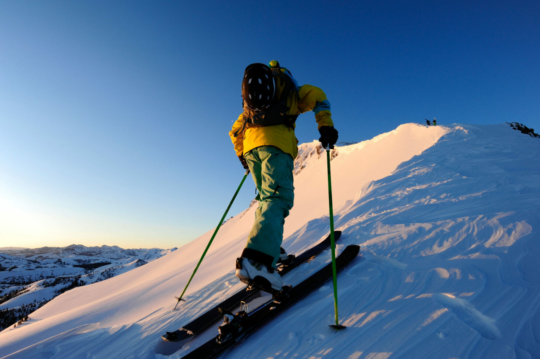 A skier skinning up a snow covered slope at sunrise in the Sierra Nevada near Lake Tahoe, California.