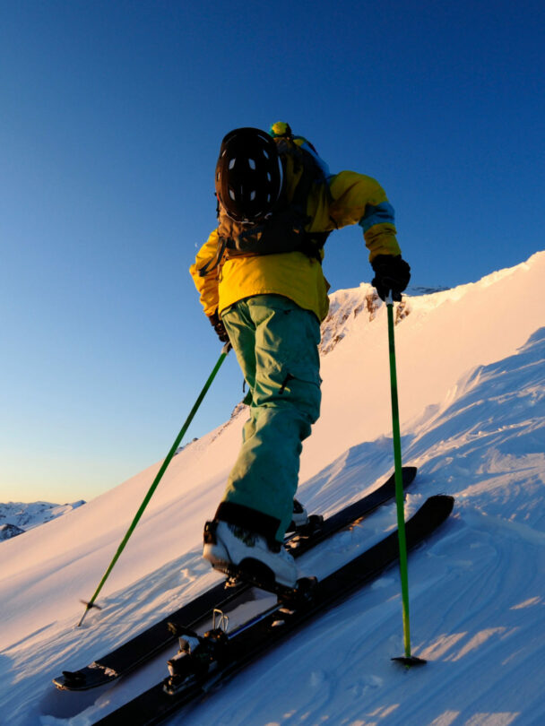 A skier skinning up a snow covered slope at sunrise in the Sierra Nevada near Lake Tahoe, California.