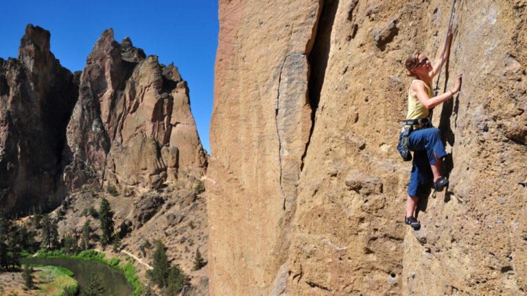 "A woman ascends a cliff at Smith Rock State Park, Oregon."