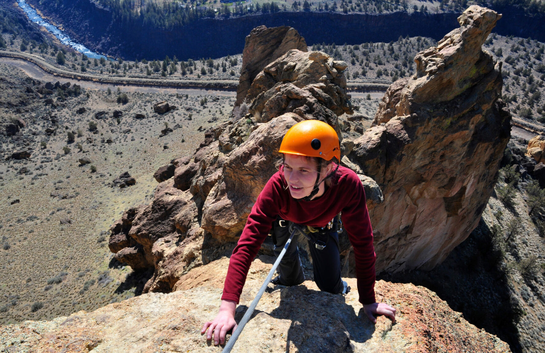 A woman nears the top of a spire at Smith Rock State Park, Oregon. The Crooked River is far below in the valley.