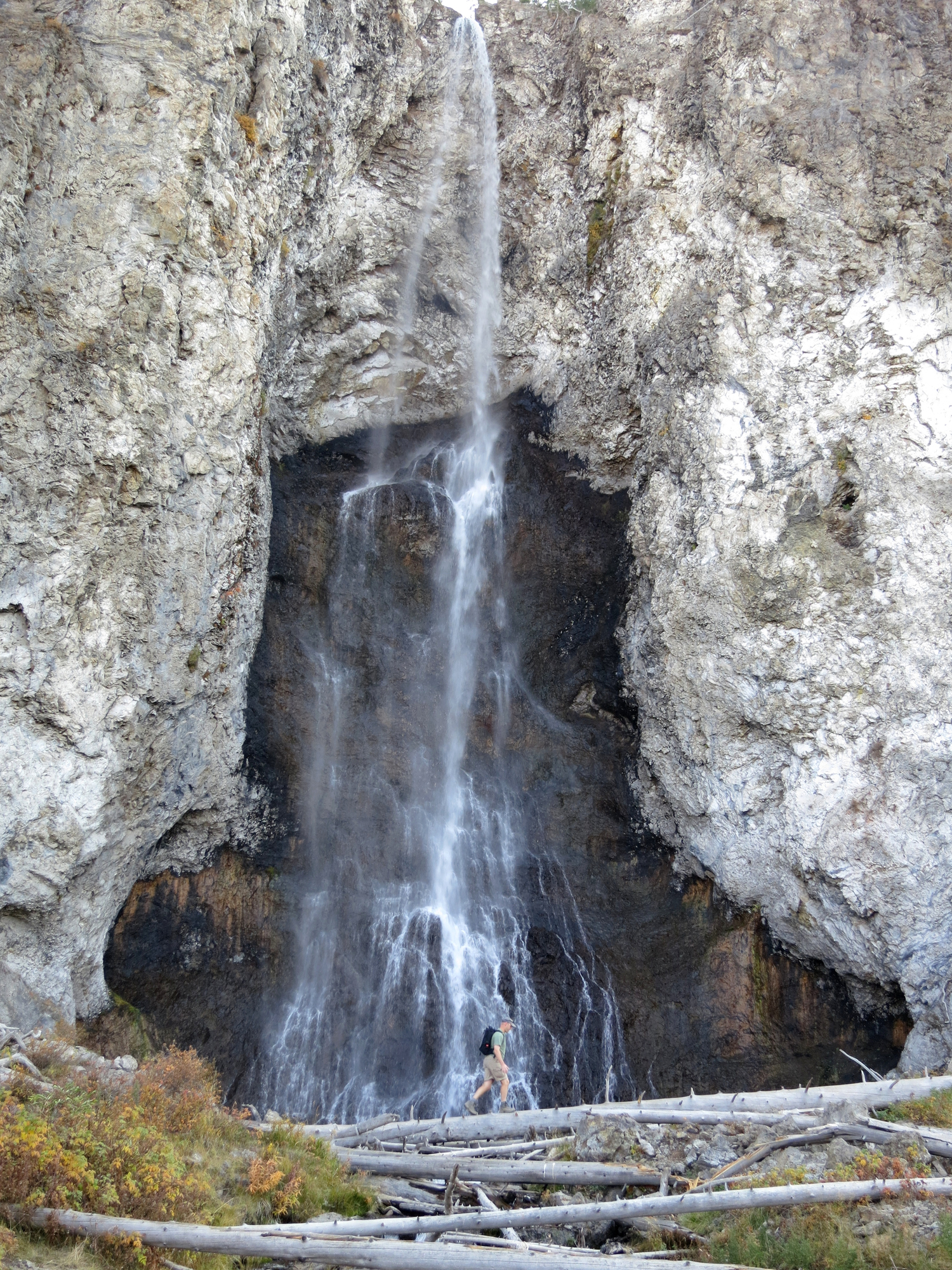 A hiker walking under the Fairy Falls in Yellowstone.
