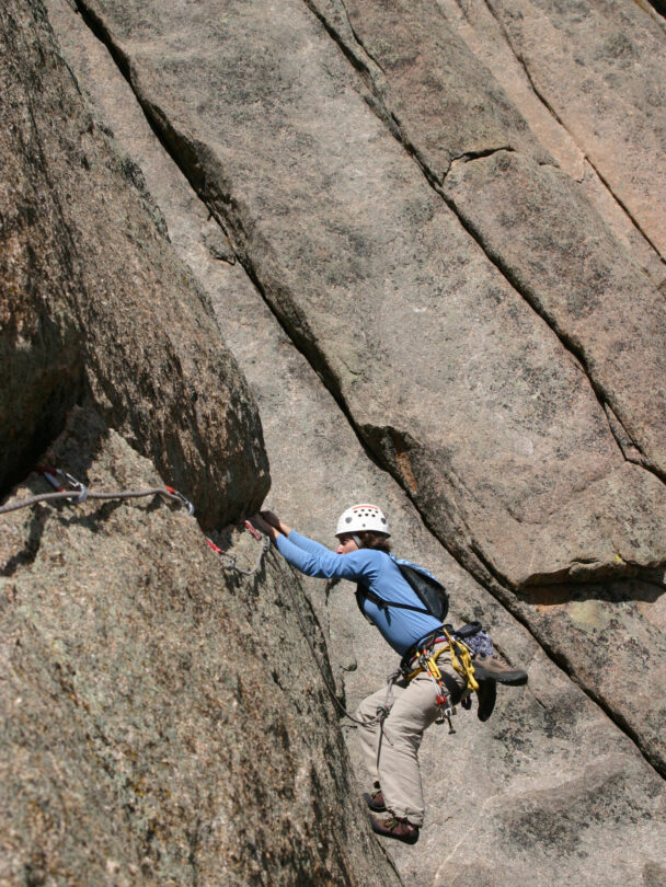 "Female climber makes the traverse from one line to the next on the fourth pitch of Orange Julius - Lumpy Ridge, Rocky Mountain National Park."