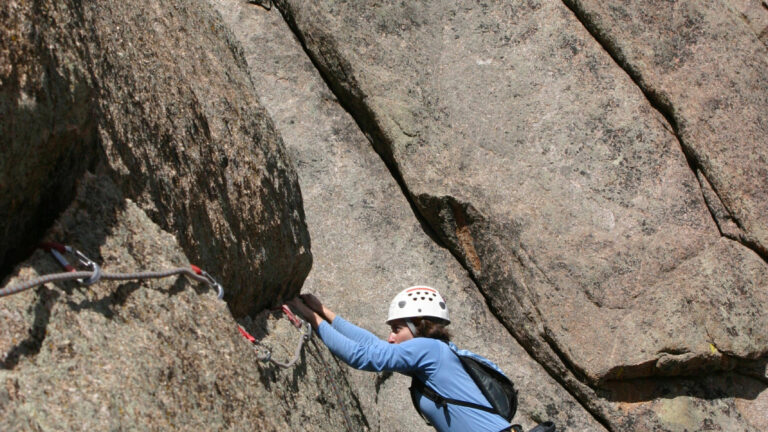 "Female climber makes the traverse from one line to the next on the fourth pitch of Orange Julius - Lumpy Ridge, Rocky Mountain National Park."