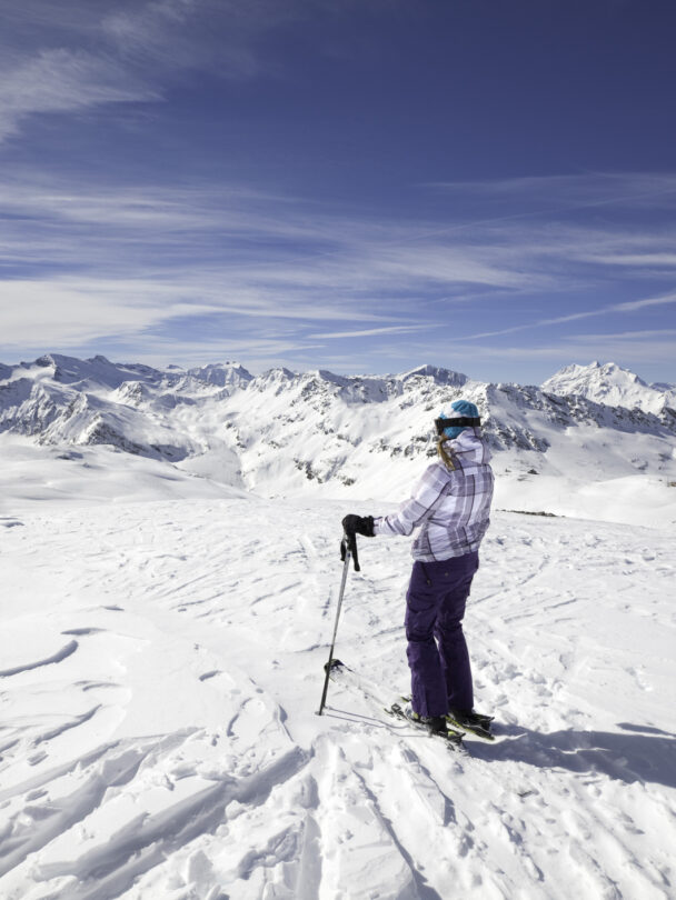 Female skier stopping to appreciate a magnificent view across the French Alps