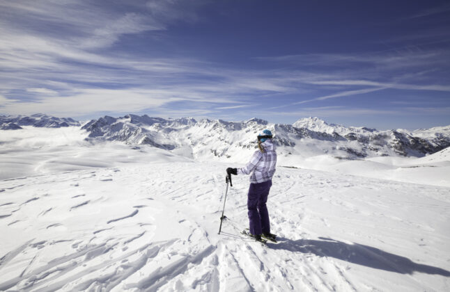 Female skier stopping to appreciate a magnificent view across the French Alps