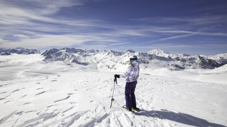 Female skier stopping to appreciate a magnificent view across the French Alps