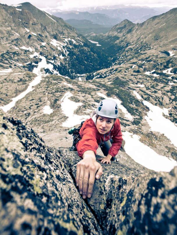 "Female climber makes the traverse from one line to the next on the fourth pitch of Orange Julius - Lumpy Ridge, Rocky Mountain National Park."