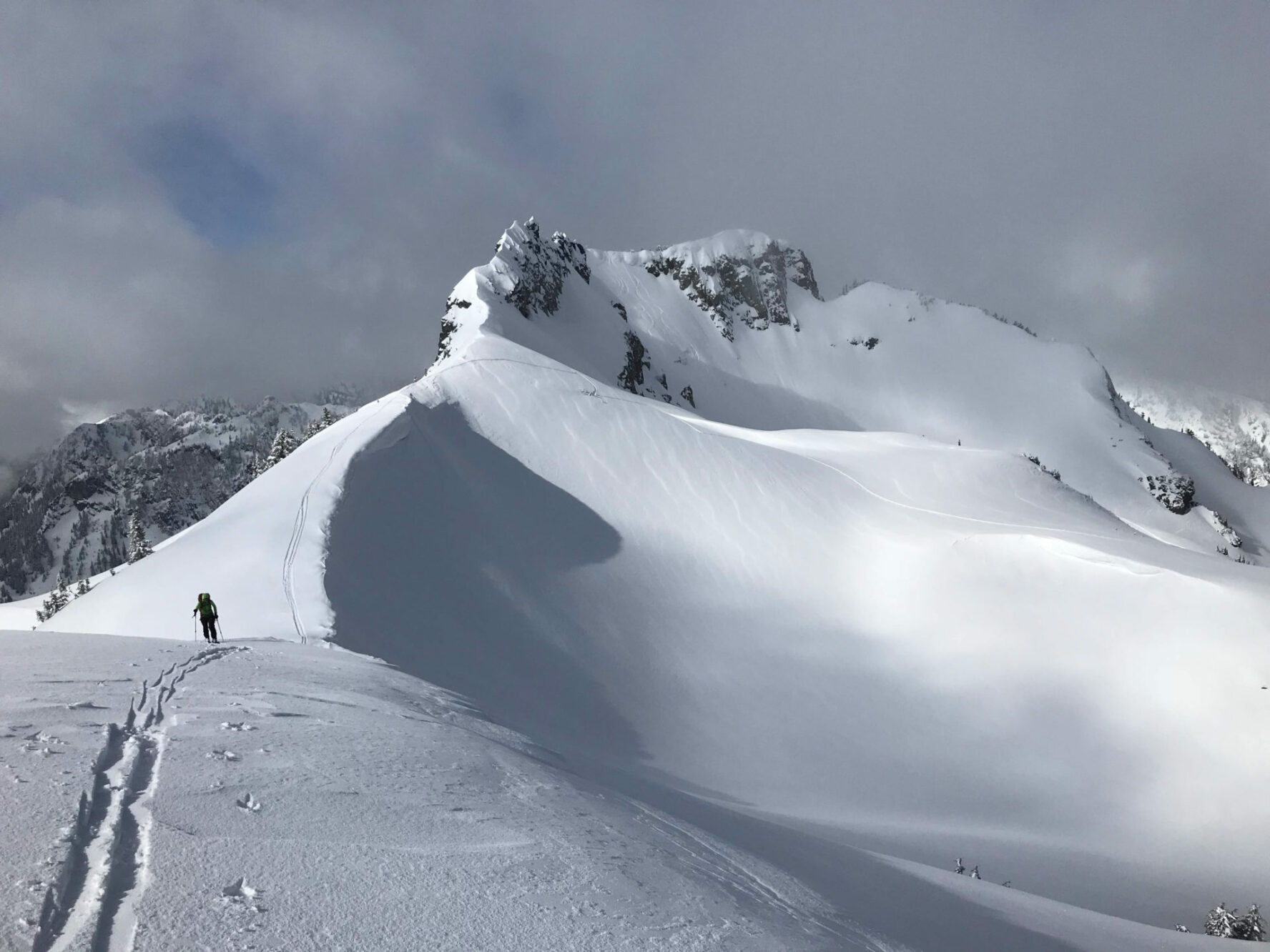 A backcountry skier moving along a snow-covered mountain ridge in Snoqualmie.