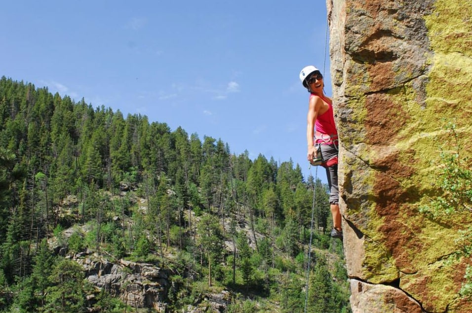 A woman rock climbing and smiling in Colorado