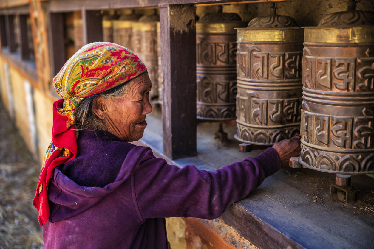 Old Tibetan woman turning the prayer wheels in a small village, Upper Mustang. Mustang region is the former Kingdom of Lo and now part of Nepal, in the north-central part of that country, bordering the People's Republic of China on the Tibetan plateau between the Nepalese provinces of Dolpo and Manang.