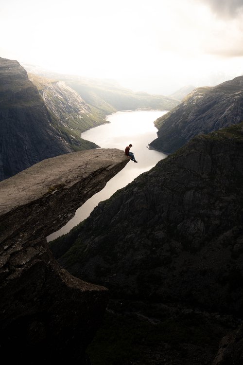 A hiker sitting at the Trolltunga cliff in Norway