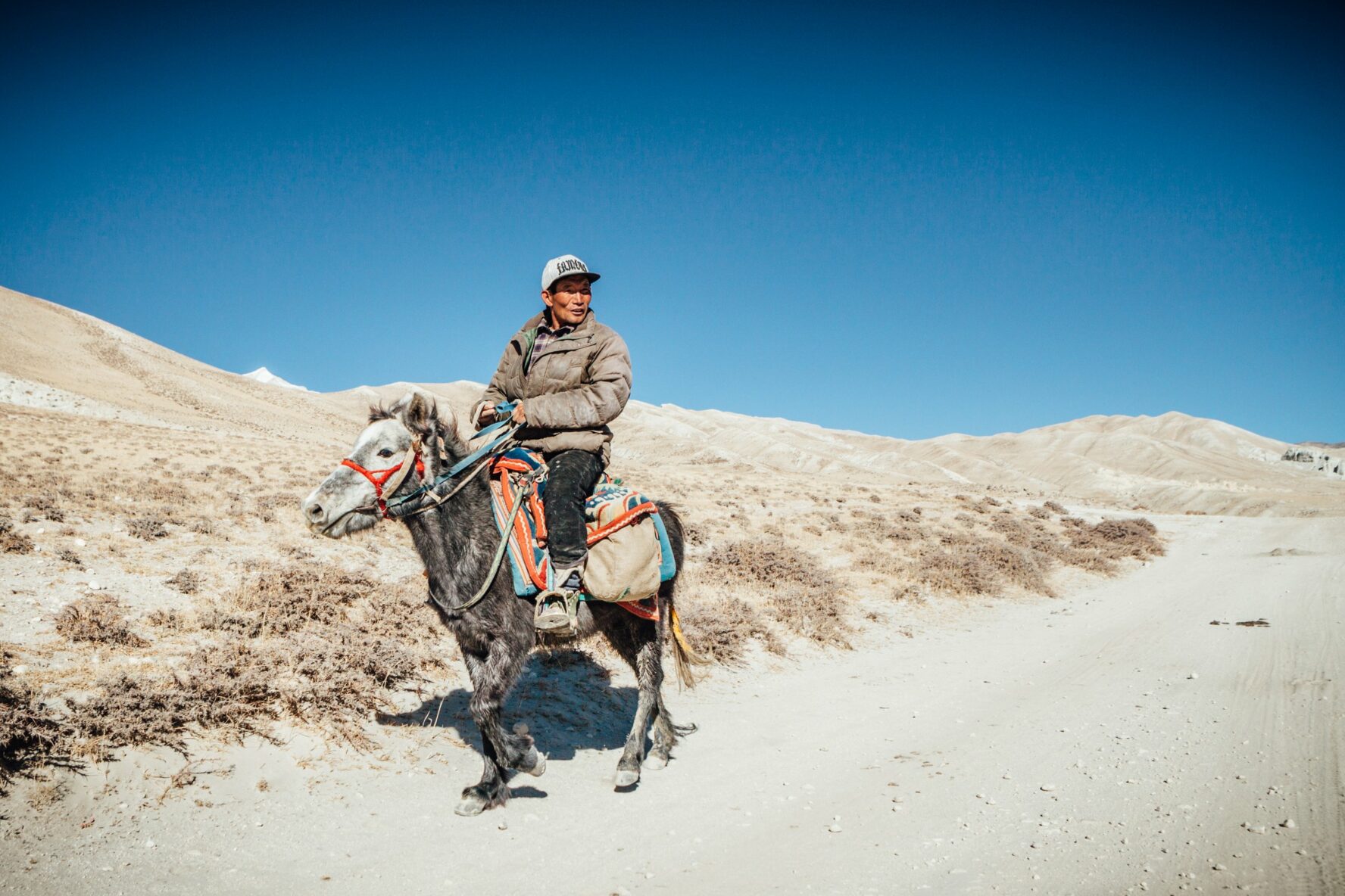 A man riding a mule on a trail in Upper Mustang