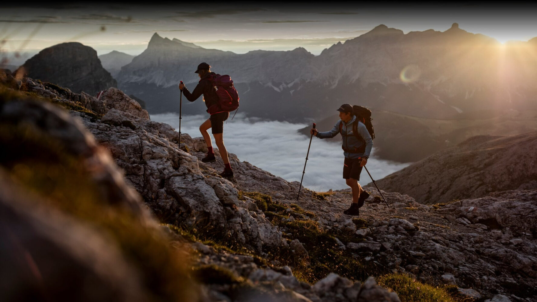 Two hikers on a guided tour in the Andes, below them a cloud-covered valley and a mountain range in the distance.