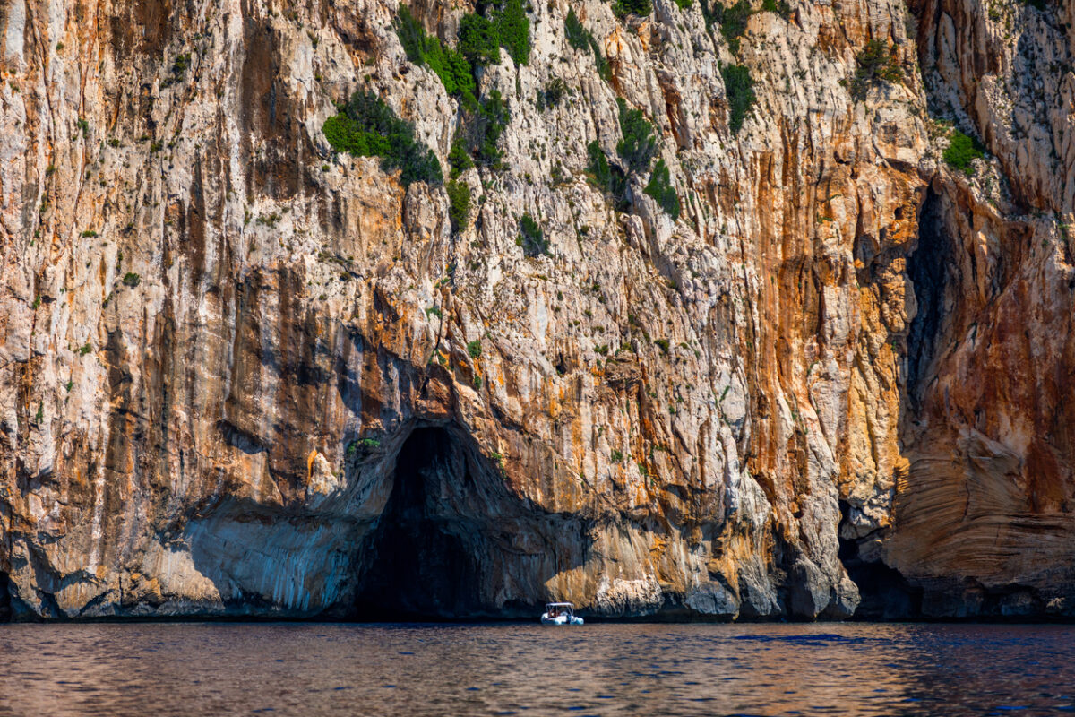 Blue sea and the characteristic caves of Cala Luna, a beach in the Golfo di Orosei, Sardinia, Italy. Big sea caves in the mediterranean coast. Sardinia, Italy.