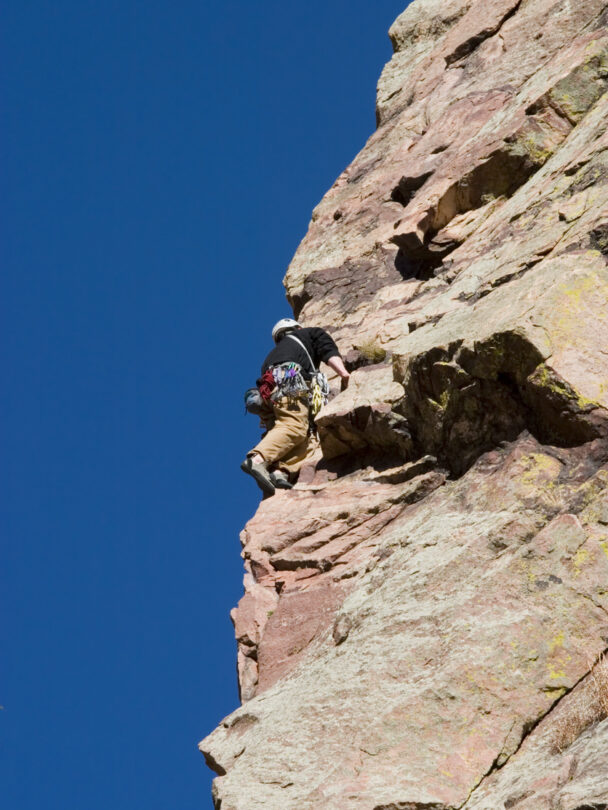 Pair of mountain climbers work together to scale a cliff high in the Colorado Rockies.