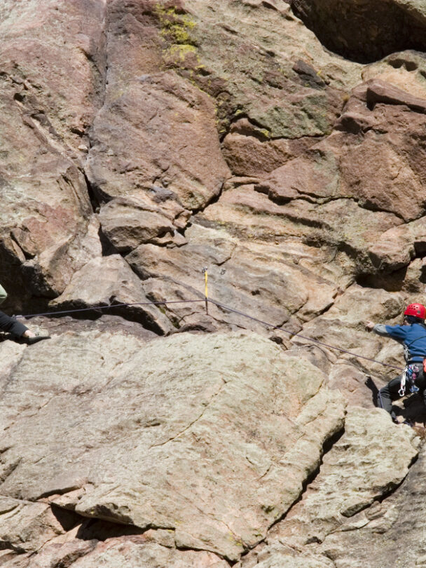 Pair of mountain climbers work together to scale a cliff high in the Colorado Rockies.
