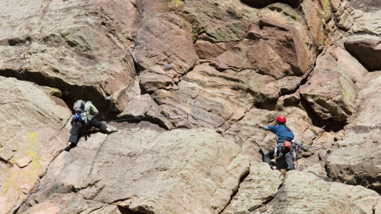 Pair of mountain climbers work together to scale a cliff high in the Colorado Rockies.