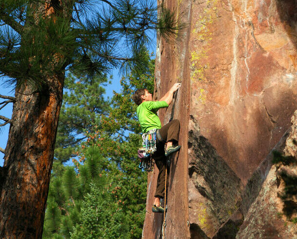 Pair of mountain climbers work together to scale a cliff high in the Colorado Rockies.