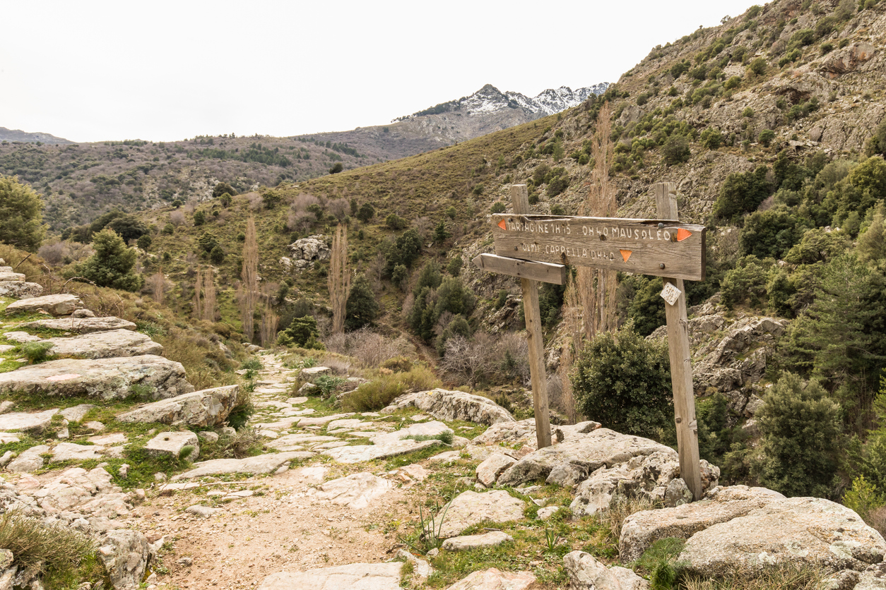 Wooden signpost giving directions on a hiking trail in Corsica
