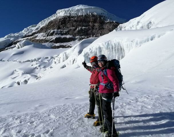 Mountain climber in Cotopaxi descending into a sea of clouds and Antisana volcano in the background, Andes Ecuador