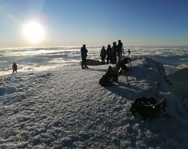 Mountain climber in Cotopaxi descending into a sea of clouds and Antisana volcano in the background, Andes Ecuador