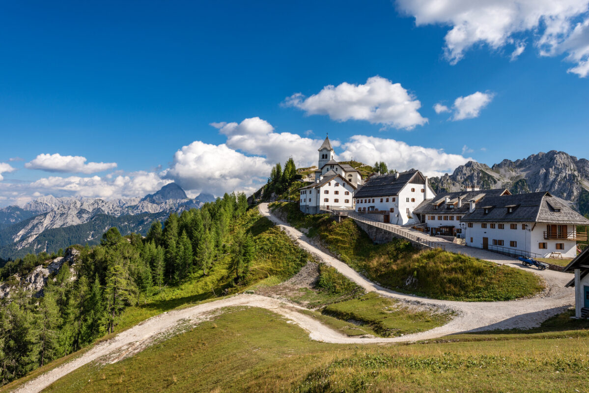 Village of Monte Santo di Lussari (1790 m) and the peak of Mangart (2677 m.) in the Julian Alps. Tarvisio, Friuli Venezia Giulia, Italy, Europe