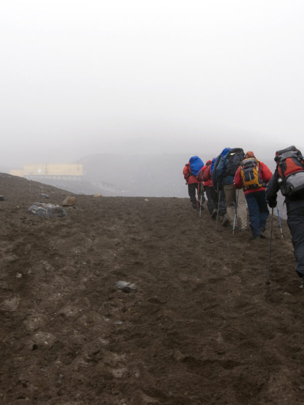 Mountain climber in Cotopaxi descending into a sea of clouds and Antisana volcano in the background, Andes Ecuador