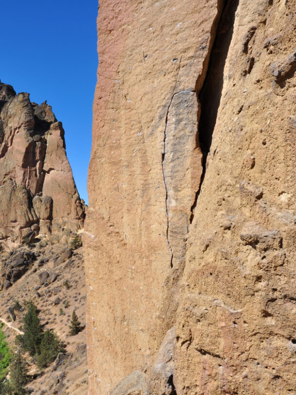 A woman nears the top of a spire at Smith Rock State Park, Oregon. The Crooked River is far below in the valley.