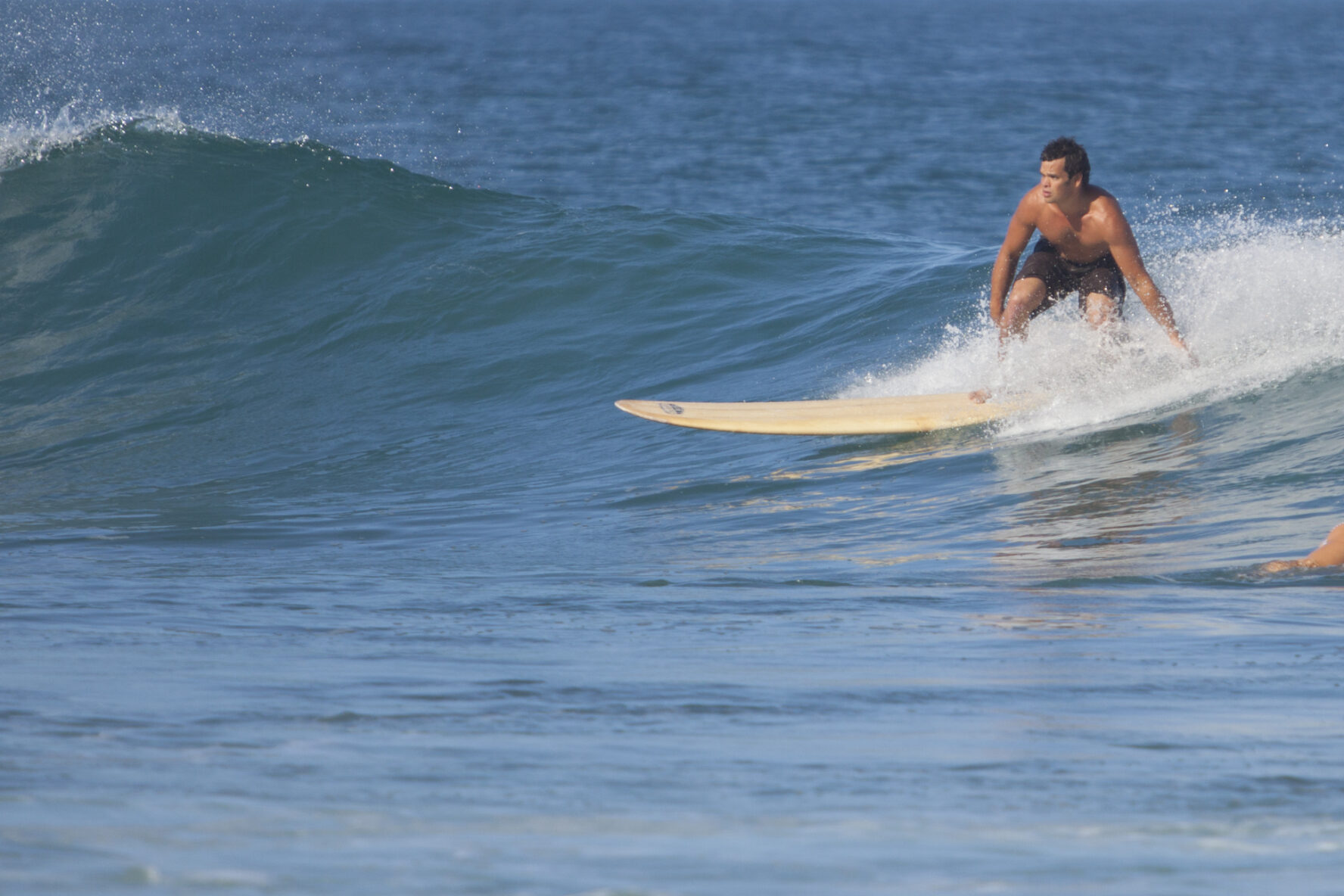 A surfer on a longboard catches a wave
