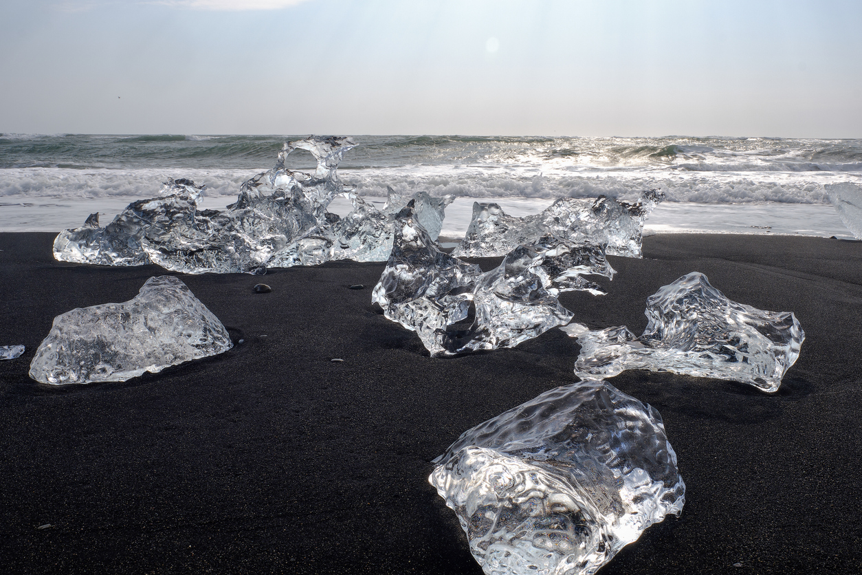 Ice floes and smaller chunks broken off larger icebergs tha thave floated out to the open ocean wash up on a black sand Iceland Beach