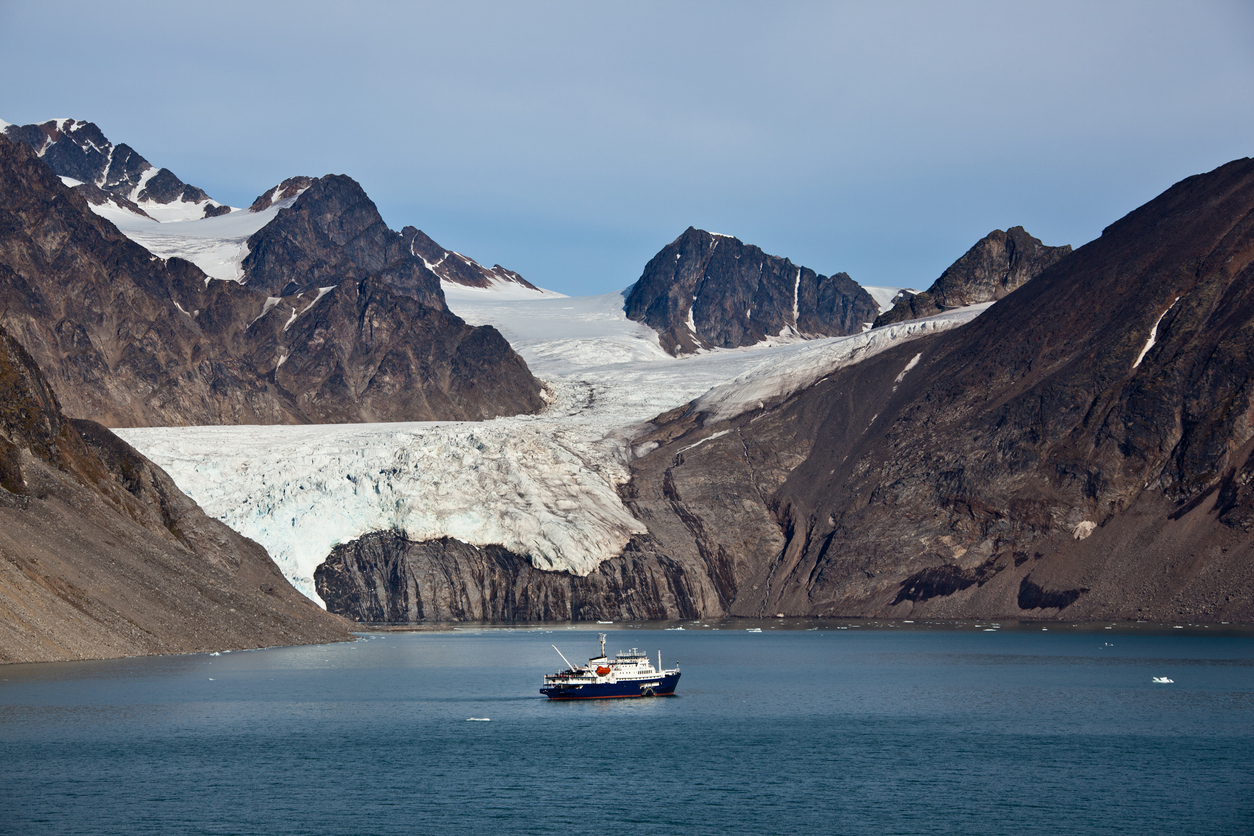 Arctic landscape in Spitzbergen -Svalbard. View across the Krossfjord to the mountains and glaciers on the other side of the Fjord. Passenger ship is anchoring in the fjord