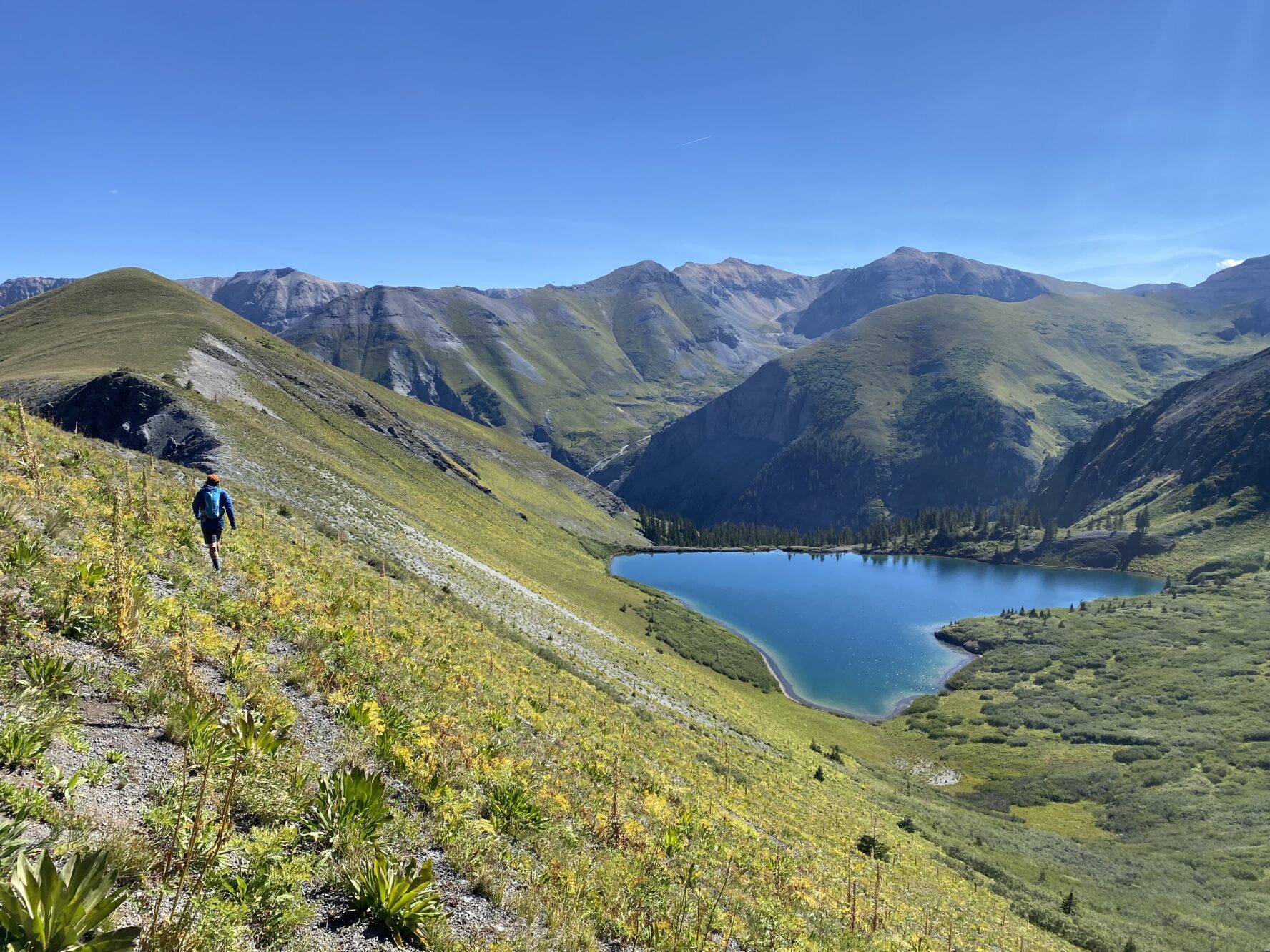 A hiker walking on a slope near a lake in Telluride
