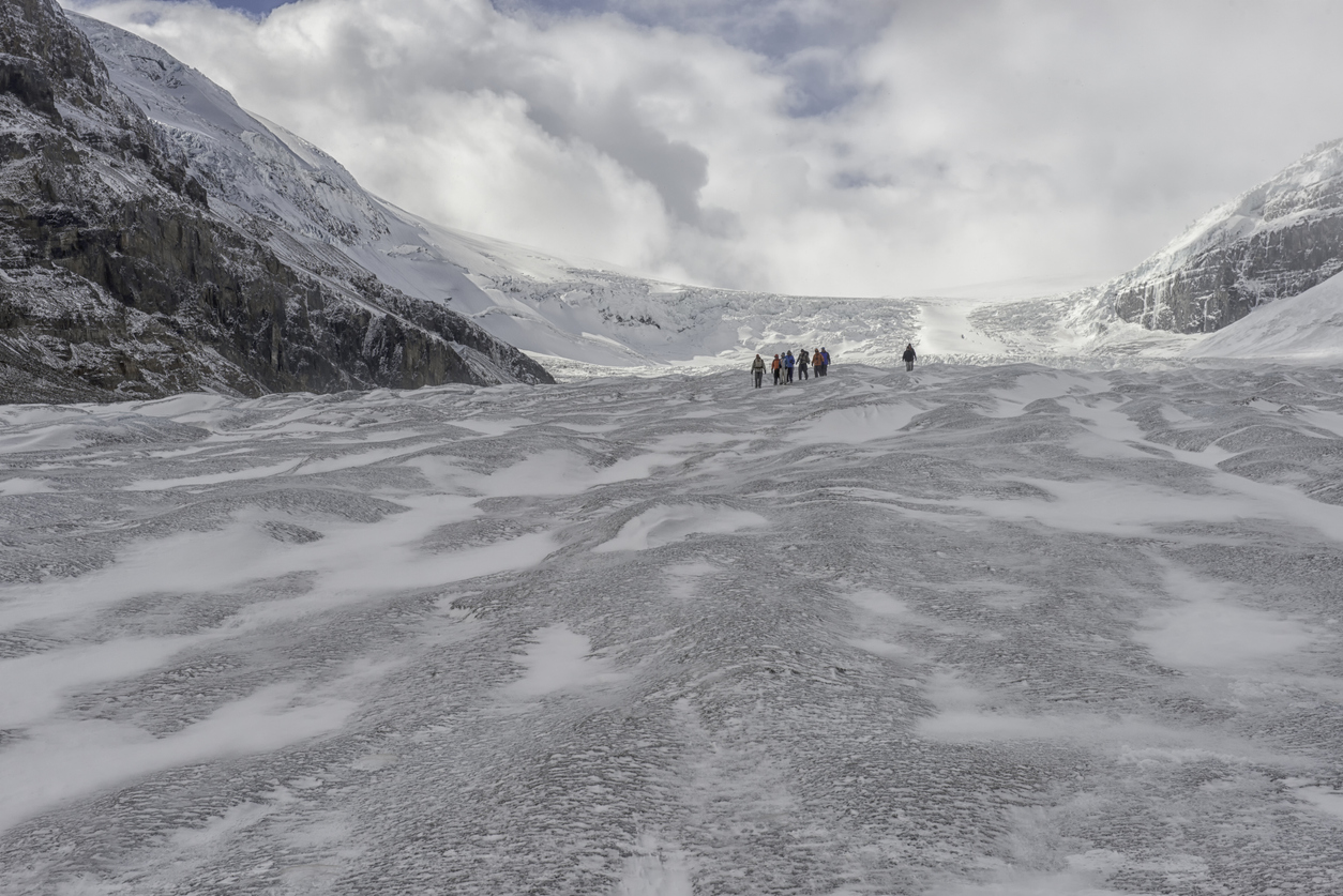 Small figures of hikers on the Athabasca Glacier provide scale.