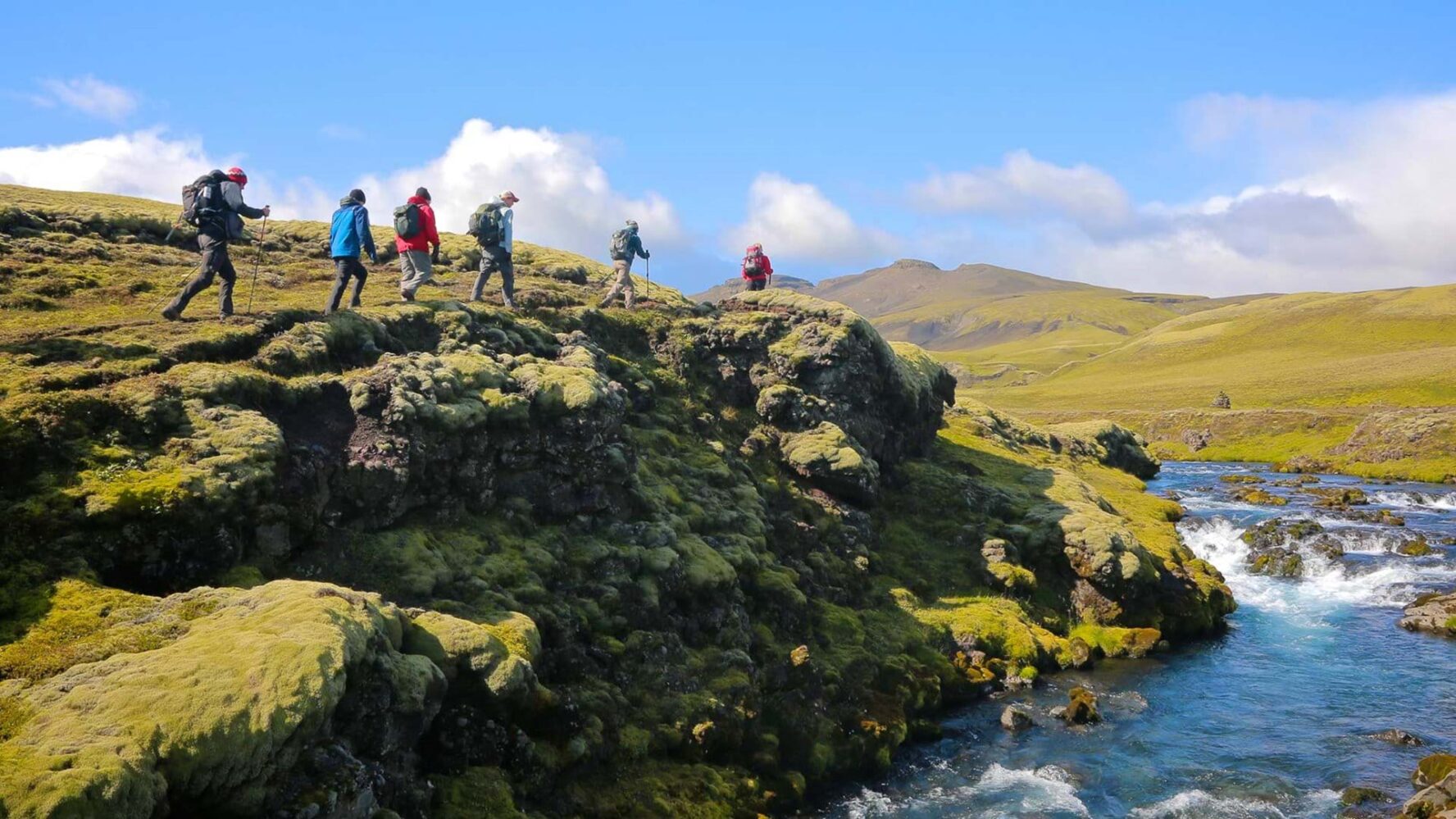 Hikers walking along a river on the Volcanic Trails route
