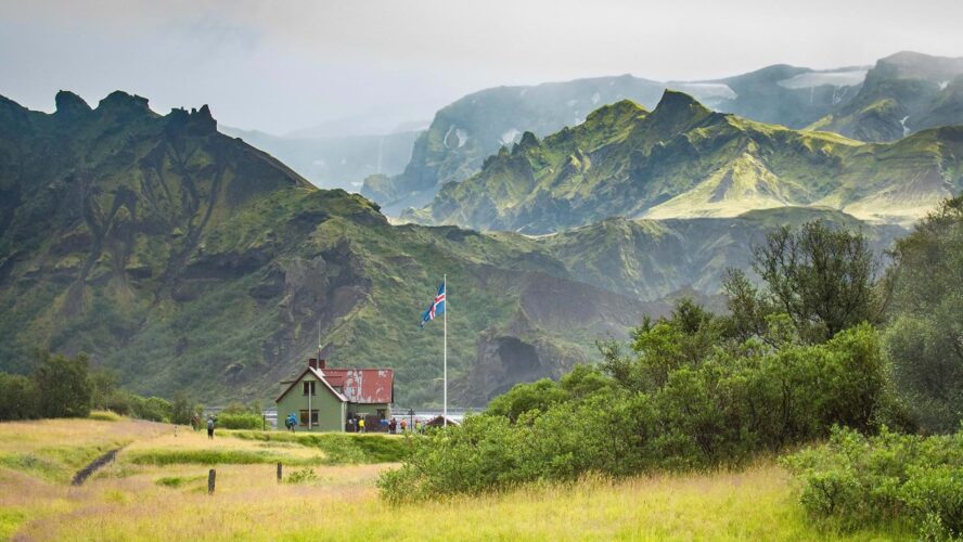 One of the many Laugavegur Trail huts nestled in between the looming mountains and green carpeting.