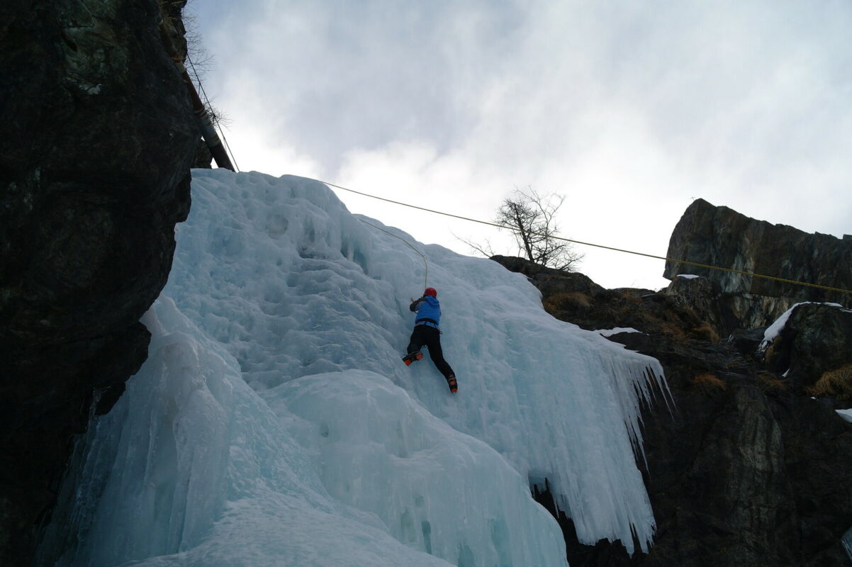 An ice climber climbing on a frozen waterfall in the Aosta Valley