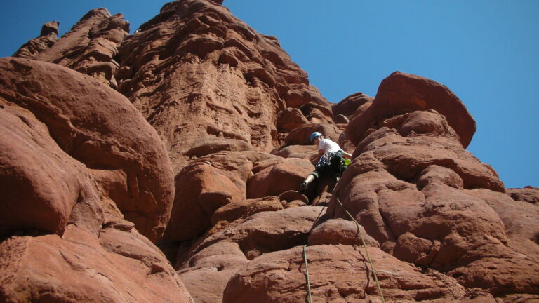 A climber ascending a tower in the Moab region
