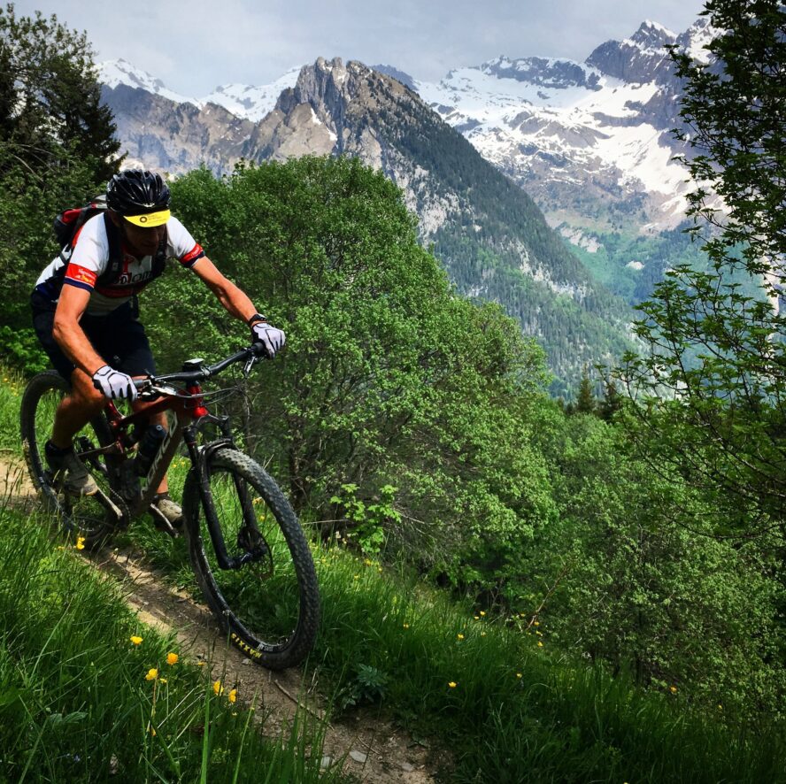 Mountain biking on the Petit Balcon Trail in Chamonix, France on a sunny (and a little snowy in the background) summer day.