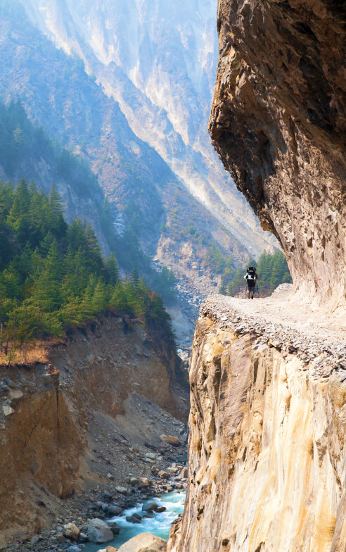 A hiker trekking along a cliff on Annapurna Circuit.