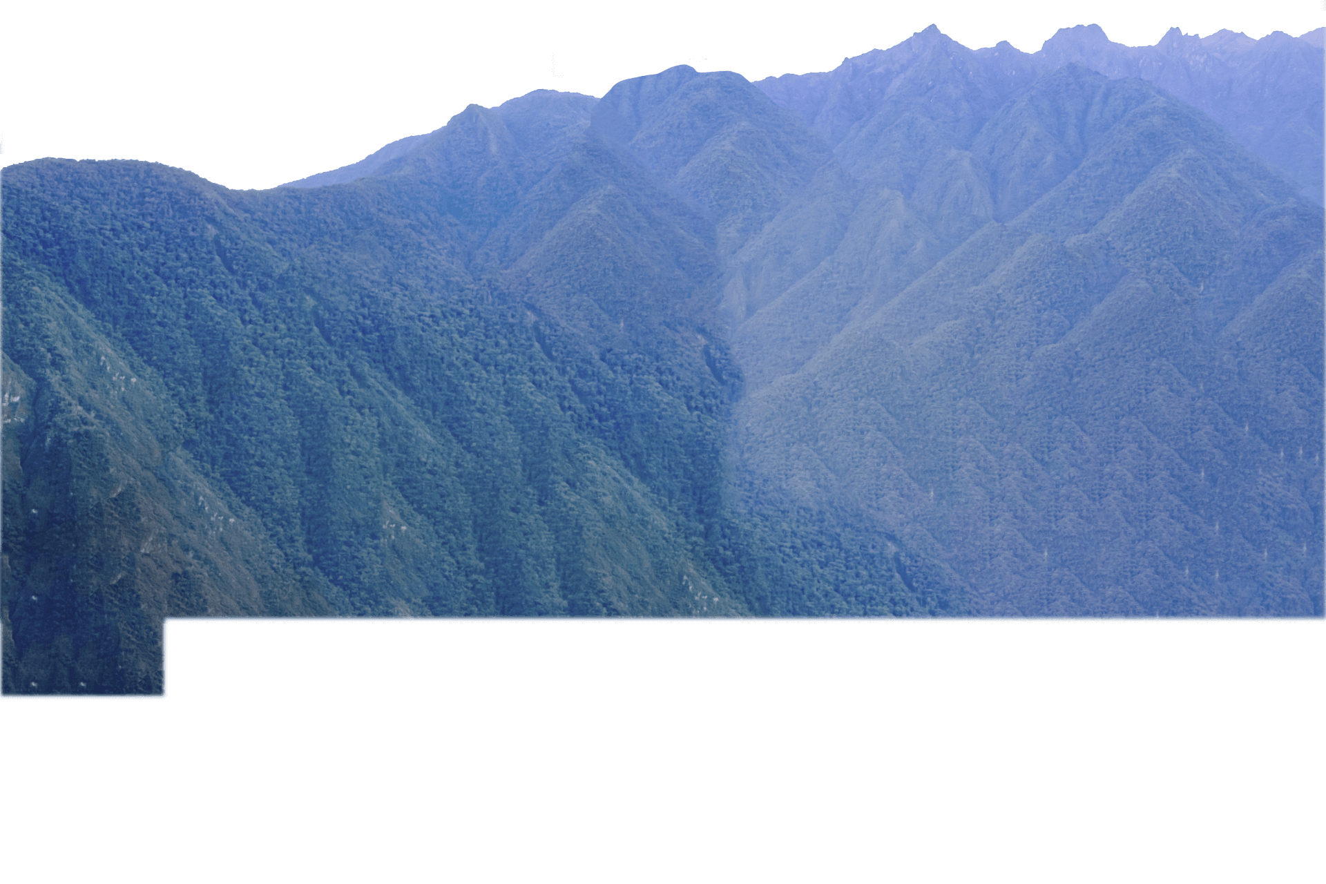 Machu Picchu is surrounded by mountains topped with lush greenery.