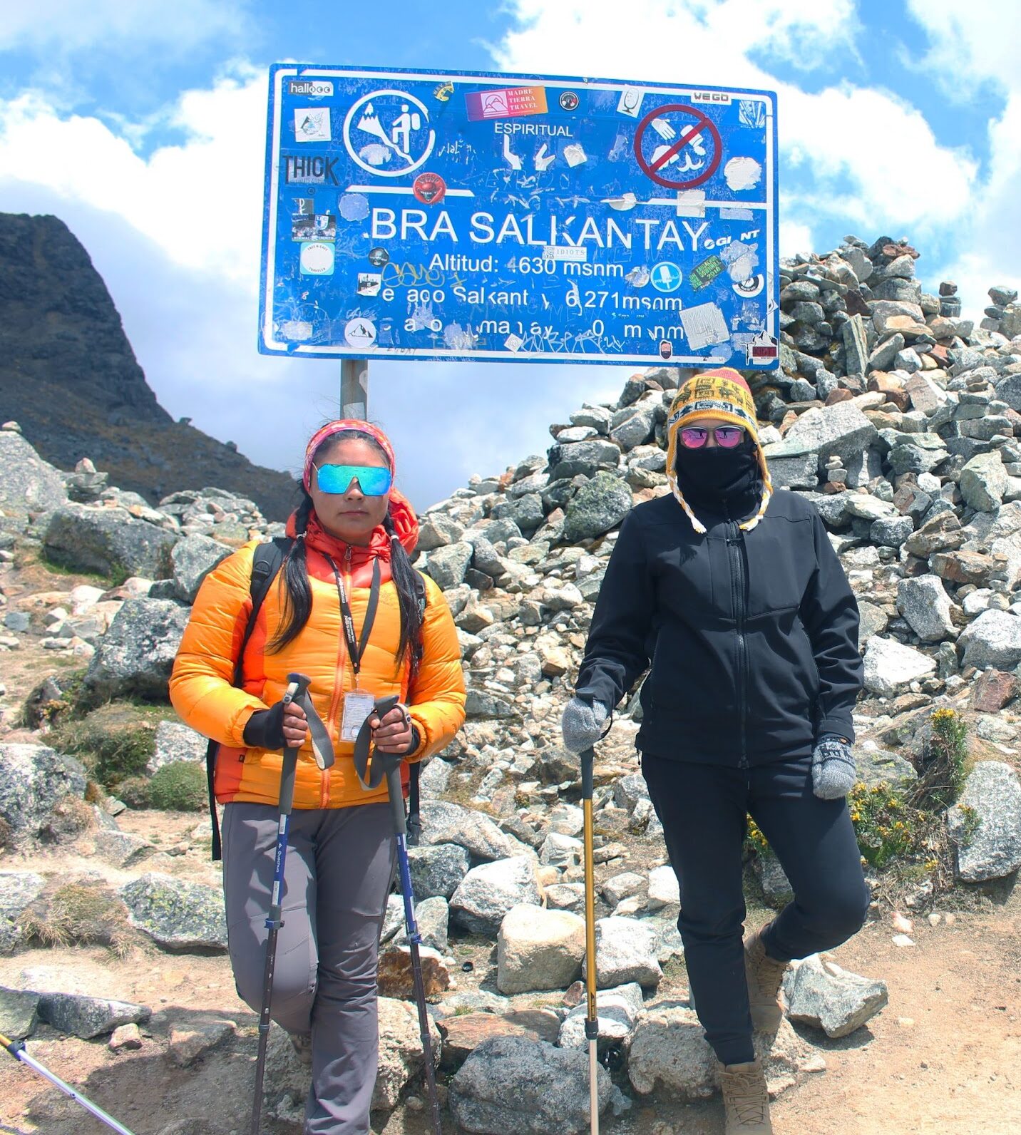Two hikers posing next to a sign at the top of the Salkantay trail in Peru