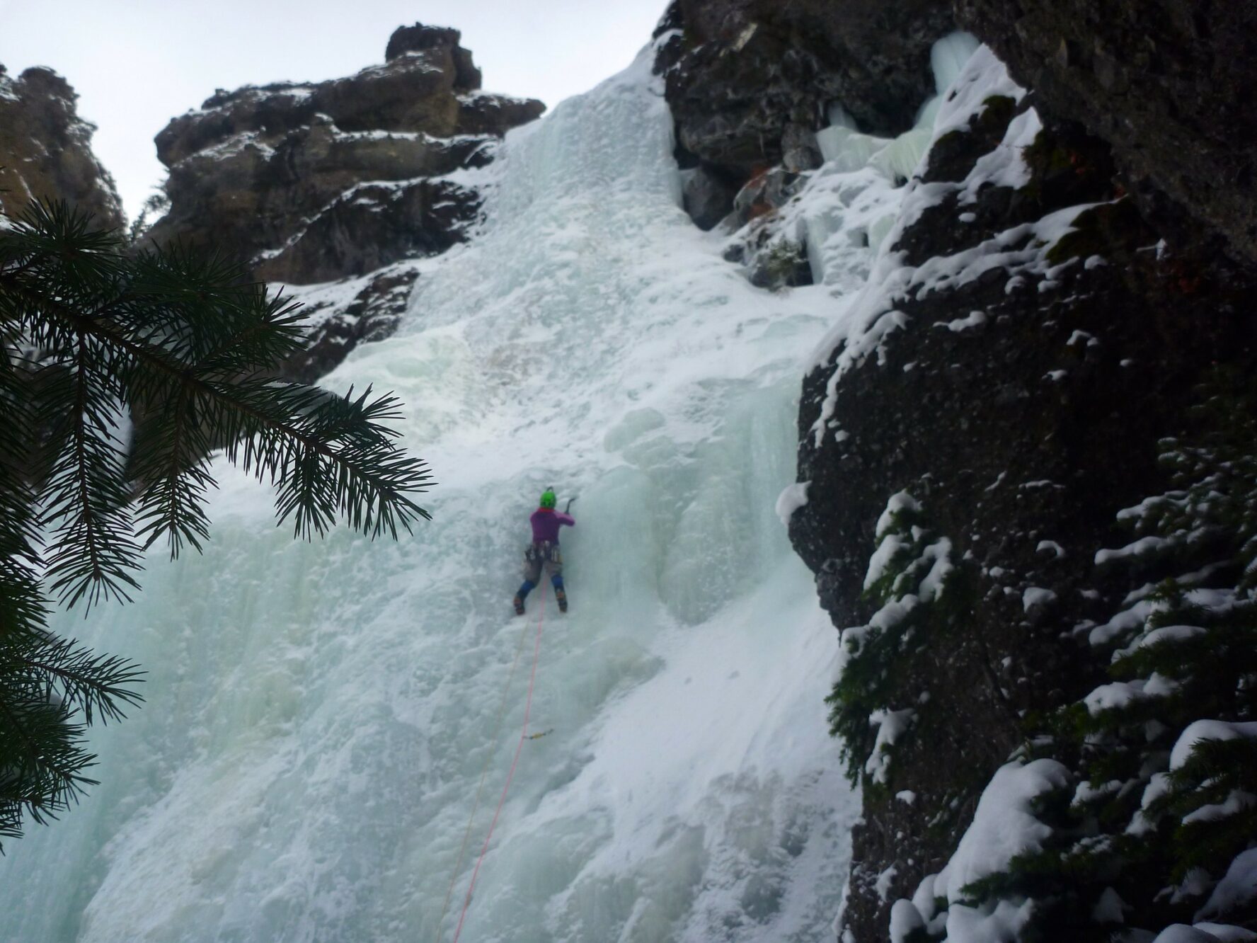 A woman ice climbing on a frozen structure