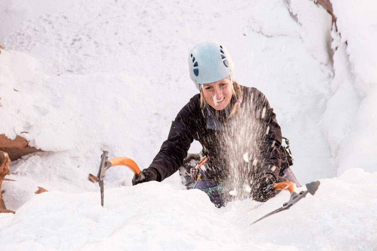 A woman ice climbing a frozen waterfall