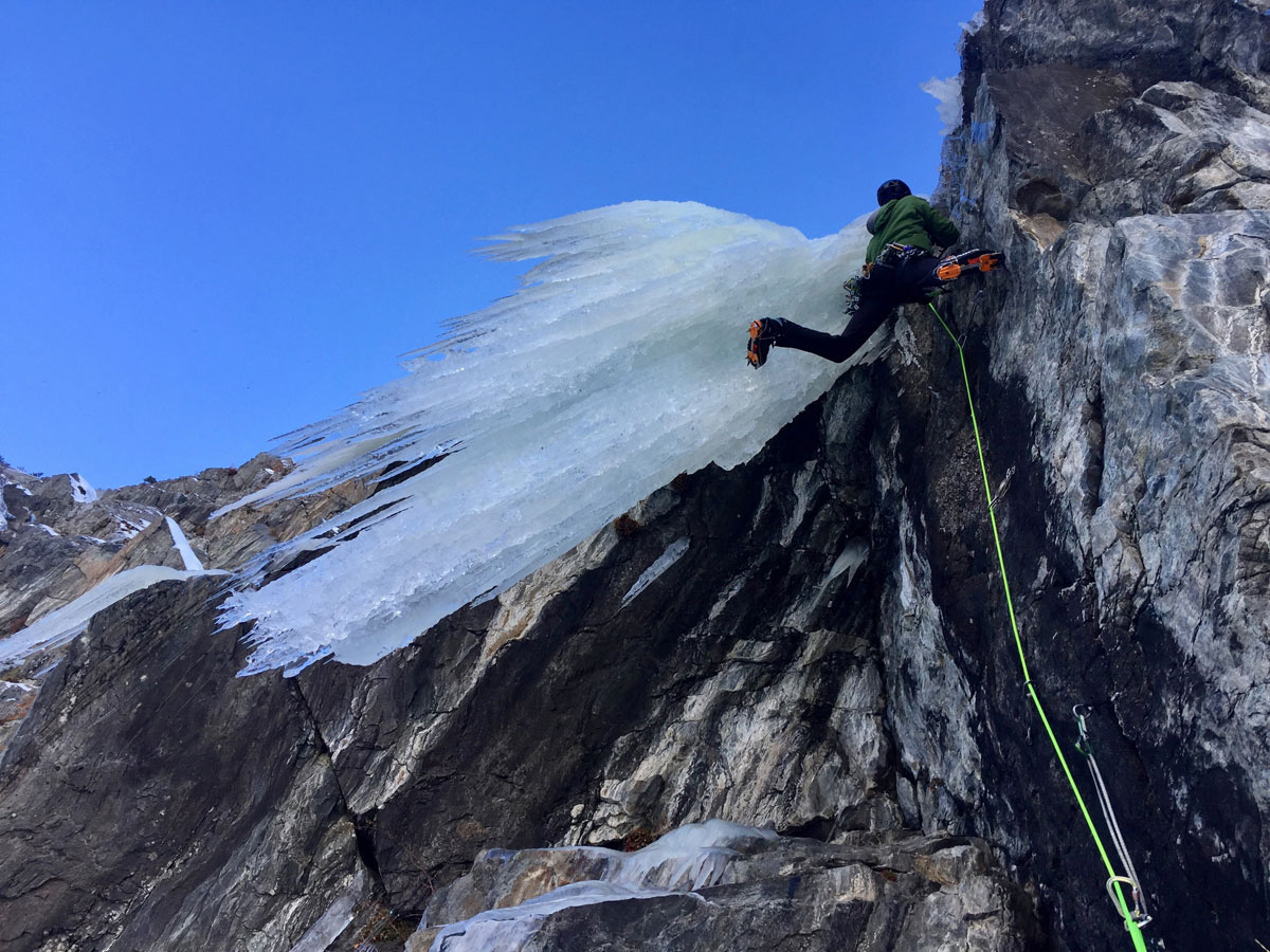 An ice climber climbing up a frozen formation in the Wasatch Mountains