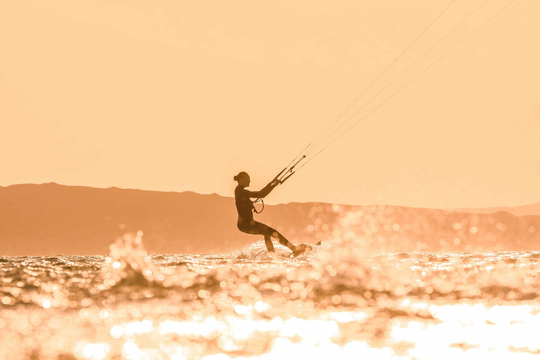 A woman kitesurfing and an orange sky on islands in the Red Sea