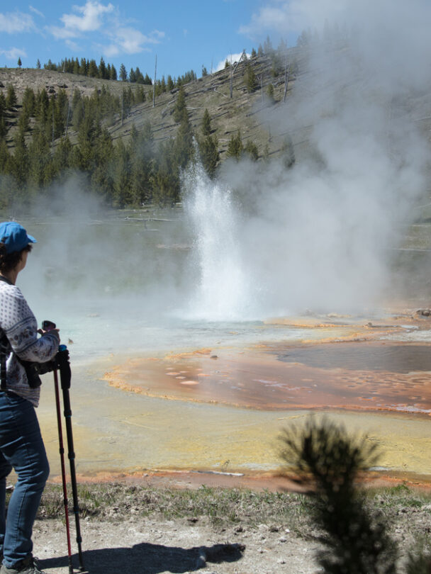 Couple relaxing and enjoying beautiful view of hot spring on vacation hiking trip. Beautiful Yellowstone Lake in the background and hot spring in foreground. Yellowstone National Park. Wyoming, USA