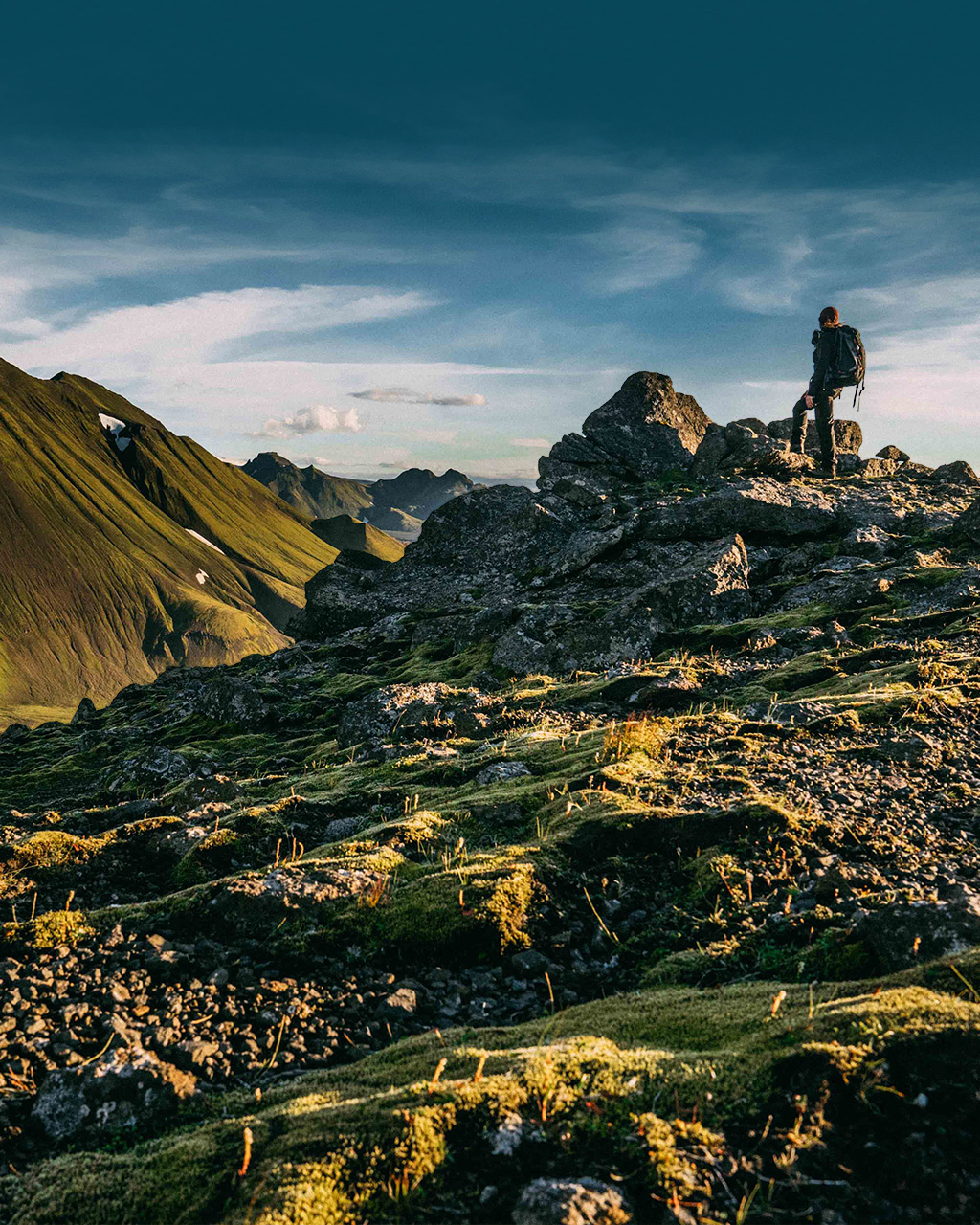 Hiker cresting a hill above the vast landscape of Southern Iceland