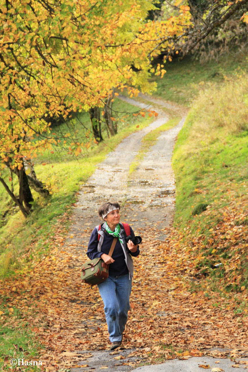 A guide on a photo walk walking across a path with leaves in the Chamonix area